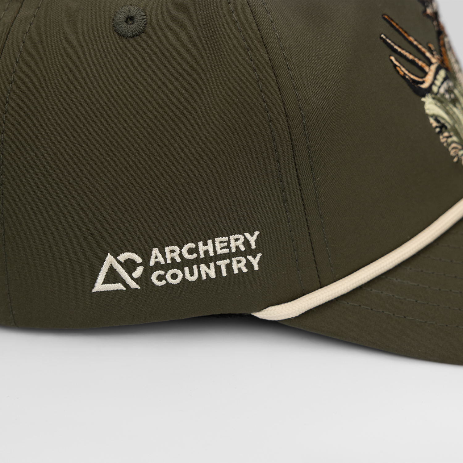 side view of faded olive hat showing white "ARCHERY COUNTRY" text on logo on side