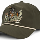 Closeup of Faded olive hat with deer on front in foliage, with white Archery Country logo