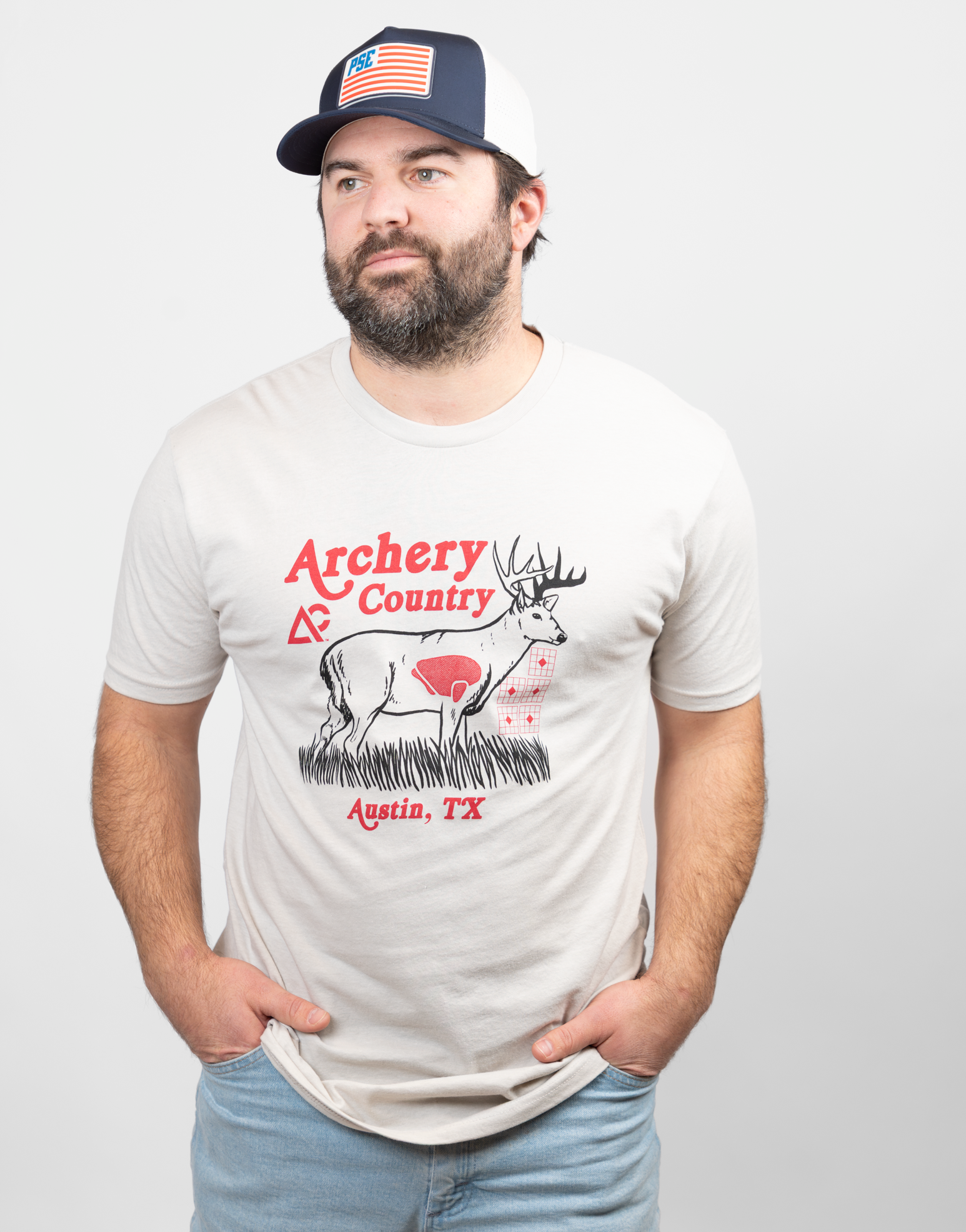 Man wearing sand tee with "ARCHERY COUNTRY Austin, TX" text and graphic of a deer